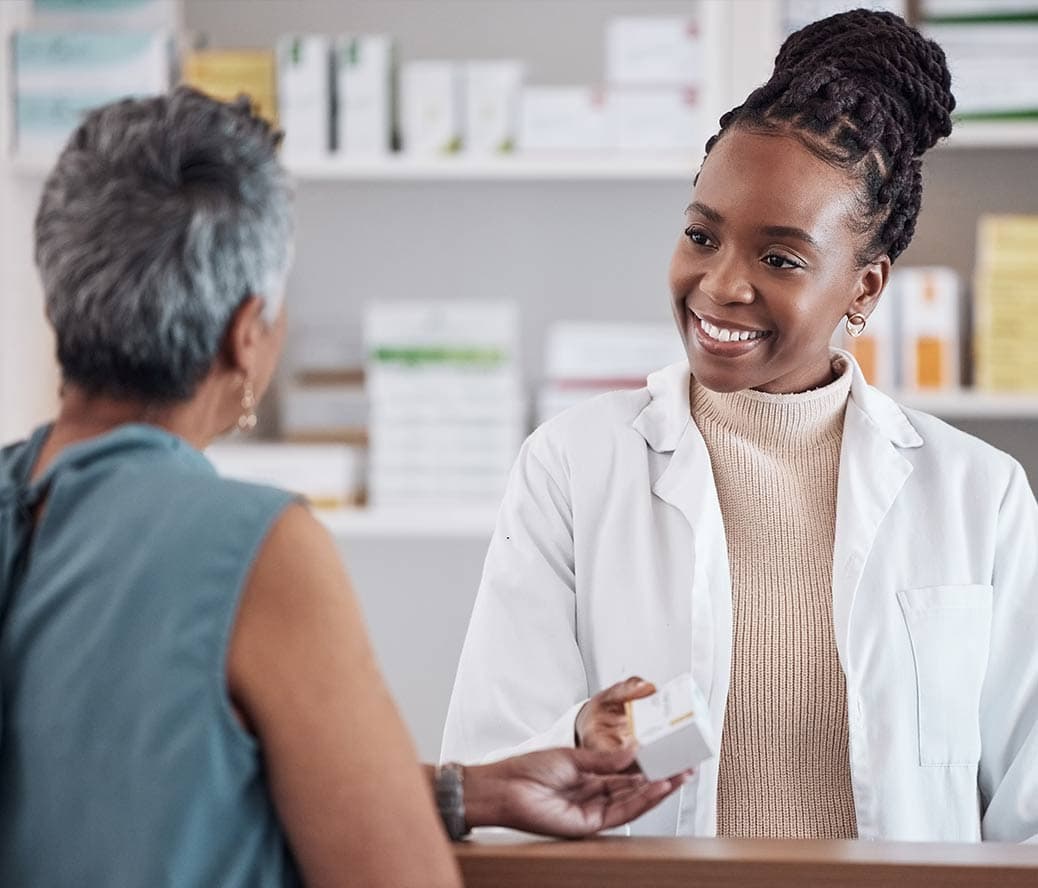 A pharmacist helps a customer check out after she used RxSense's GlobalBin to get the best price.